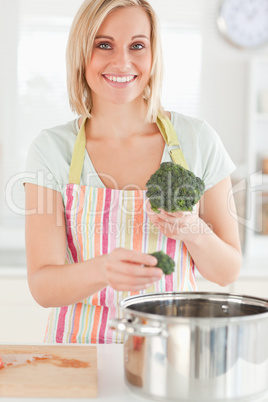 Close up of a woman cooking broccoli looks into the camera