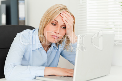 Blonde business woman touching her forehead being tired