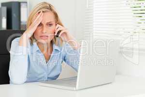 Frustrated businesswoman sitting in front of her notebook on pho