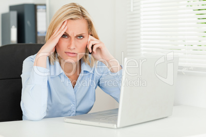Frustrated blonde businesswoman on phone looks into camera