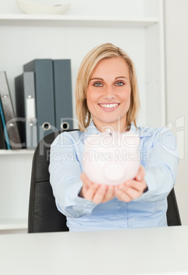 Cute smiling businesswoman holding a piggy bank