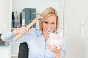 Smiling blonde woman wanting to destroy her piggy bank