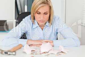 Sulking woman sitting in front of an shattered piggy bank with l