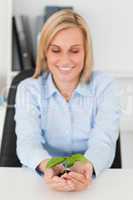 Smiling businesswoman looking at little green plant