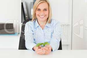 Woman holding a little plant smiies into camera