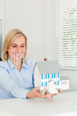 Gorgeous businesswoman showing model house looking at it