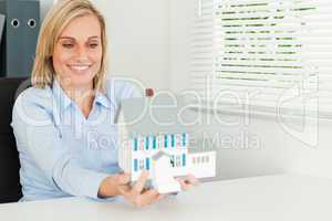 Gorgeous businesswoman presenting model house looking at it