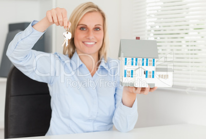 Gorgeous blonde businesswoman presenting model house and keys lo