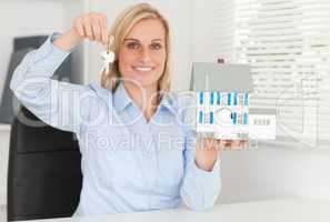 Gorgeous blonde businesswoman presenting model house and keys lo