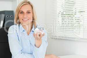 Gorgeous blonde businesswoman showing miniature house looks into