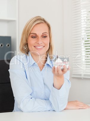 Gorgeous blonde businesswoman showing miniature house looking at