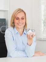 Gorgeous blonde businesswoman showing miniature house looking at