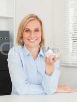 Gorgeous blonde businesswoman showing miniature house looking in