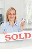 Gorgeous blonde businesswoman showing miniature house and SOLD s