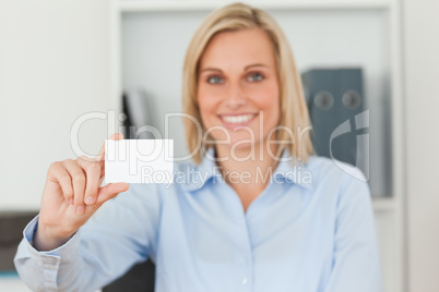 Blonde businesswoman holding a card looks itno camera