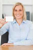 Smiling blonde businesswoman holding a card looks itno camera
