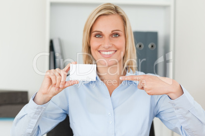 Businesswoman pointing at a card looks itno camera