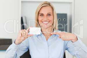 Businesswoman pointing at a card looks itno camera