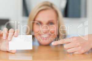 Businesswoman pointing at a card crouching behind her desk looks