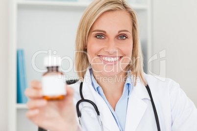 Gorgeous blonde doctor holding medicine to camera