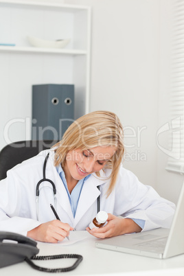 Doctor writing something down while holding medicine