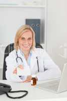 Smiling doctor holding prescription looks into camera