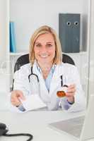 Charming blonde doctor holding prescription and medicine smiles