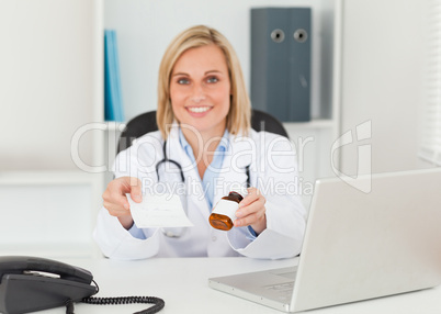 Charming doctor holding prescription and medicine smiles into ca