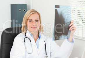 Charming doctor holding x-ray looks into camera
