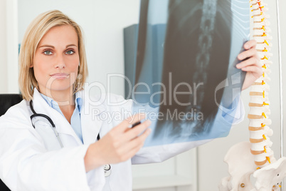 Serious doctor looking at x-ray looks into camera
