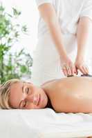 Blonde woman relaxing on a massage lounger during stone therapy