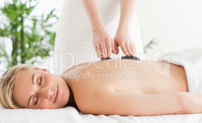 Blonde relaxed woman experiencing a stone therapy with closed ey