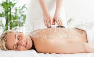 Blonde relaxed woman experiencing a stone therapy with closed ey
