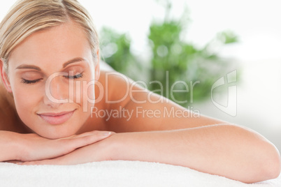 Close up of a blonde smiling woman relaxing on a lounger with ey
