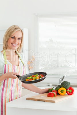 Portrait of a woman showing cutted peppers in pan