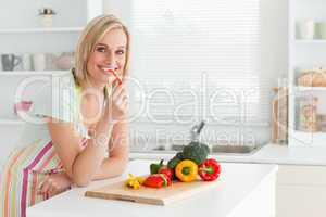 Portrait of a woman eating red peppers