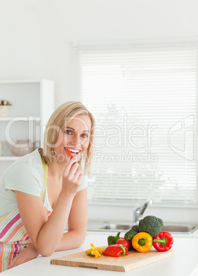 Portrait of a blonde woman eating red peppers