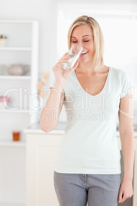 Smiling woman drinking water while standing