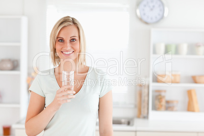 Charming woman holding glass filled with water while standing lo