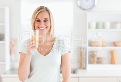 Charming woman holding glass filled with orange juice while stan