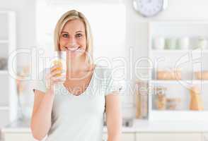 Charming woman holding glass filled with orange juice while stan