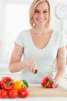 Woman cutting peppers looks into camera