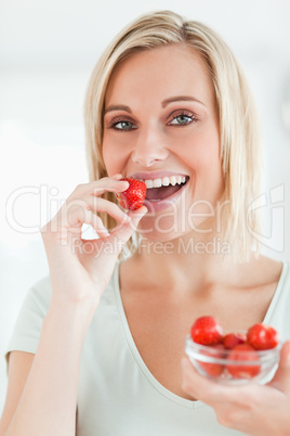 Portrait of a woman enjoying eating strawberries looking into th