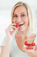 Portrait of a woman enjoying eating strawberries looking into th
