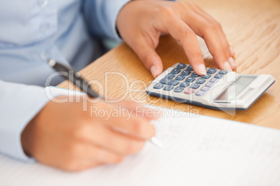 Feminine hands using a pen and a calculator