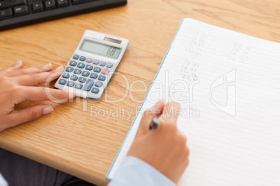 Feminine hands using a calculator and a pen