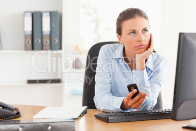 Thoughtful working woman holding a mobile phone