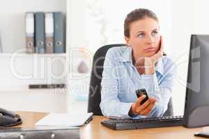 Thoughtful working woman holding a mobile phone