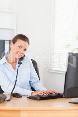 Secretary answering the phone while typing on her keyboard