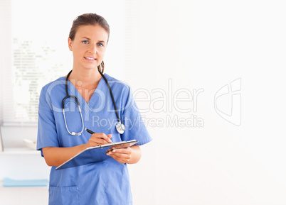 Young nurse writing in a folder with a pen